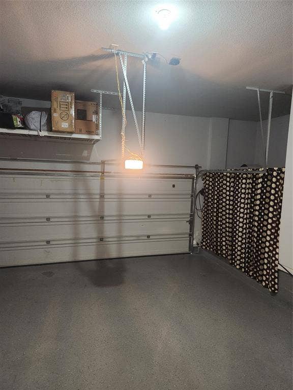 3038 Ivy Hill Lane, Irving, TX 75063 Garage featuring a roll-up door, overhead lighting, an exposed ceiling, and shelving