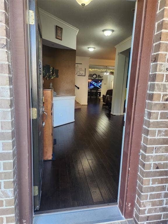 3038 Ivy Hill Lane, Irving, TX 75063 Brick exterior, dark wood-finish flooring, recessed lighting, crown molding, and a built-in staircase