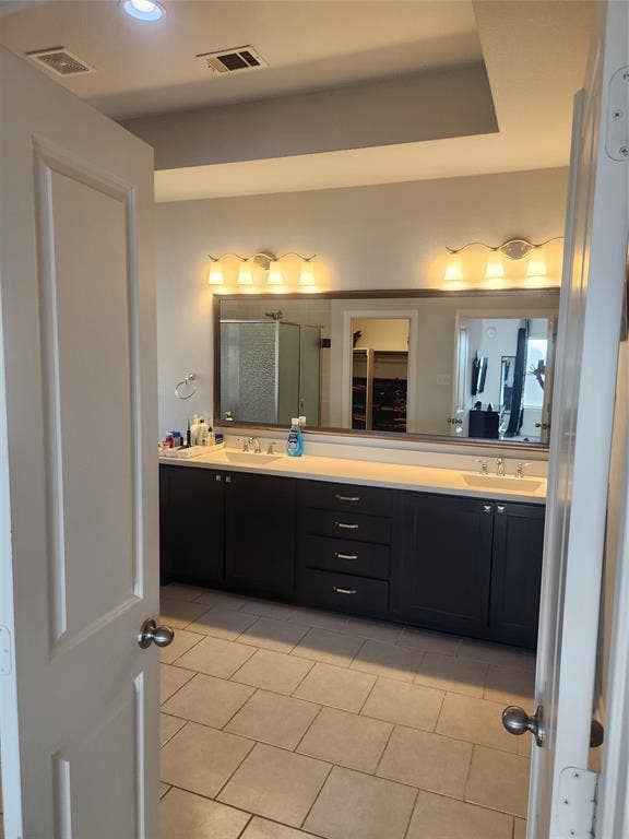 3038 Ivy Hill Lane, Irving, TX 75063 Dual vanity with undermount sinks, extensive countertop space, dark wood cabinetry, tile flooring, and recessed ceiling lighting