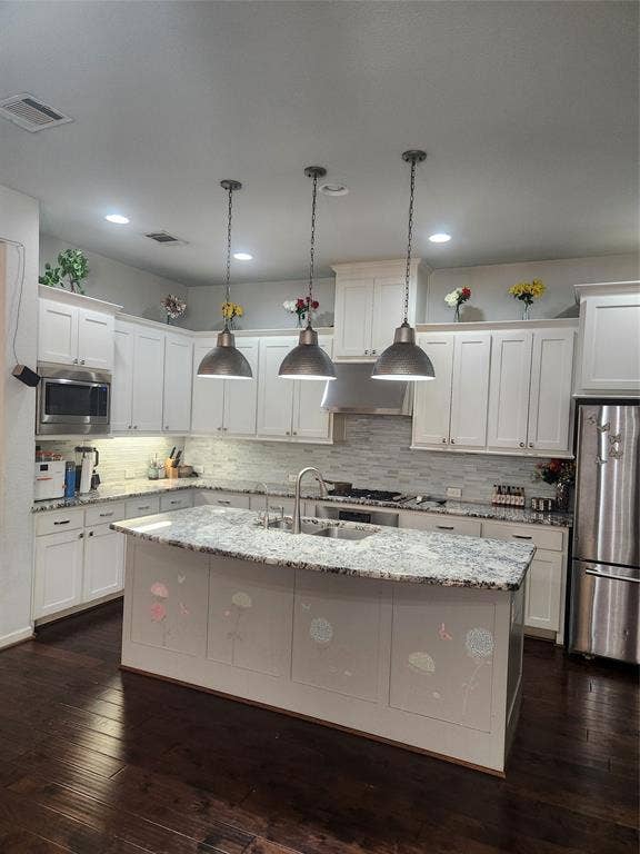 3038 Ivy Hill Lane, Irving, TX 75063 Kitchen featuring a large island with a stone countertop, dark wood-finish flooring, white cabinetry, stainless steel appliances, and a tile backsplash