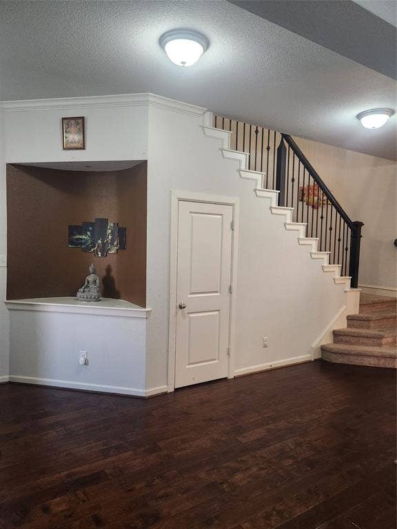3038 Ivy Hill Lane, Irving, TX 75063 Dark wood-finish flooring, white painted walls, crown molding, built-in niche, and a staircase with dark wrought iron spindles
