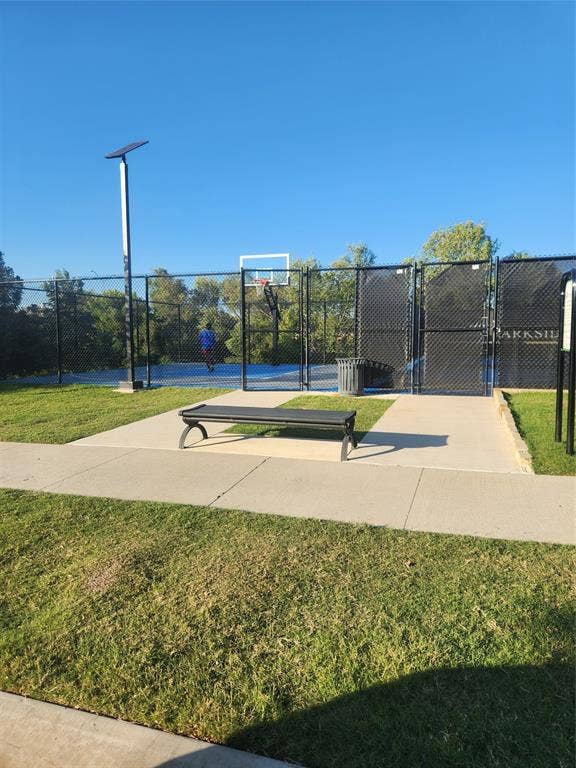 3038 Ivy Hill Lane, Irving, TX 75063 Community basketball court featuring a blue playing surface, black chain-link fencing, and a permanent bench