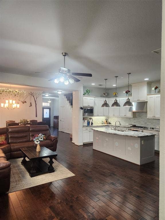 3038 Ivy Hill Lane, Irving, TX 75063 Expansive wood-finish flooring throughout, kitchen with white cabinetry, large center island with stone countertop, stainless steel appliances, and pendant lighting