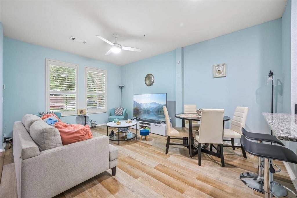 2209 Stonepark Place, McKinney, TX 75071 Wood-finish flooring throughout, two large windows with plantation shutters, a ceiling fan with integrated lighting, a built-in breakfast bar with a stone-finish countertop, and a dining area