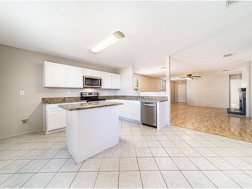Kitchen featuring white cabinetry, granite countertops, a central island, and stainless steel appliances