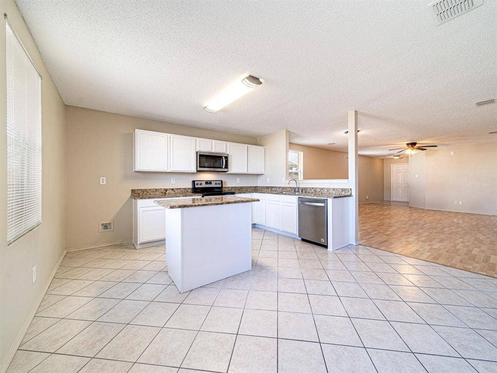 Kitchen featuring white cabinetry, an island, stainless steel appliances, and tile flooring