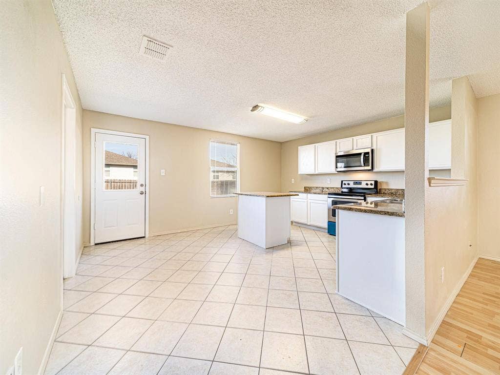 Kitchen featuring white cabinetry, stainless steel microwave, and a freestanding range
