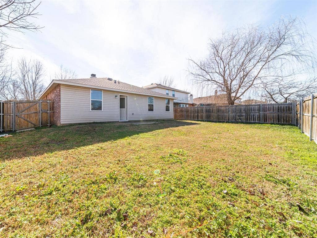 Expansive backyard featuring a partial brick exterior, horizontal siding, and a wood fence enclosure