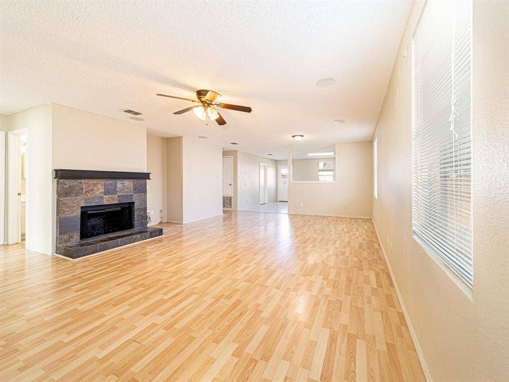 Living space featuring wood-finish flooring, a fireplace with a stone surround, multiple windows with blinds, a ceiling fan, and recessed lighting