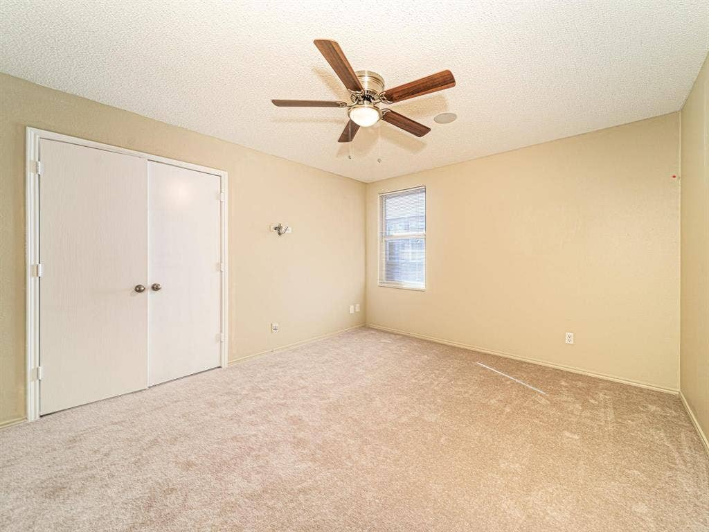 Carpeted room featuring a ceiling fan with integrated lighting, a single window, and bi-fold closet doors
