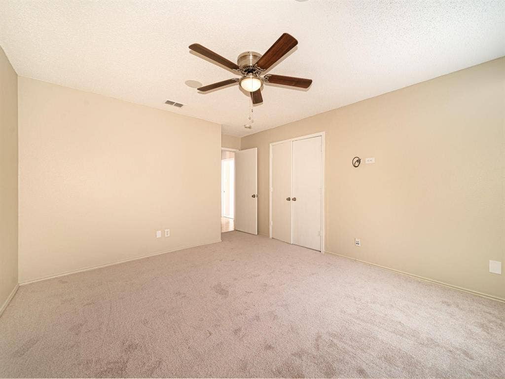 Carpeted flooring, neutral wall tones, ceiling fan with light fixture, and white bi-fold closet doors