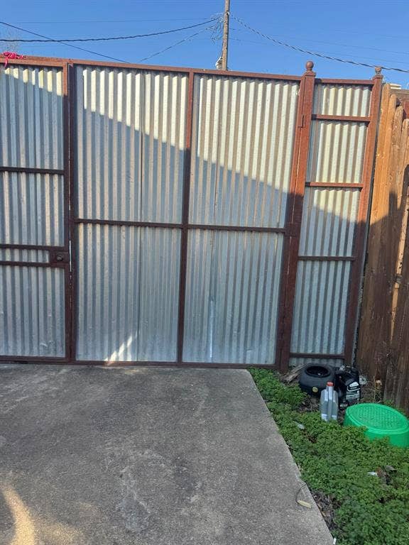544 Pleasant Meadows Lane, Dallas, TX 75217 Corrugated metal gate with a dark-toned frame and a concrete pad.