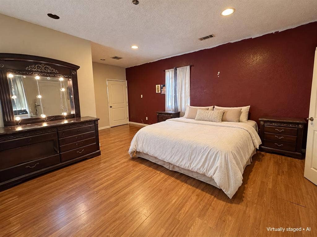 544 Pleasant Meadows Lane, Dallas, TX 75217 Spacious bedroom featuring wood-look flooring, recessed lighting, and a contrasting accent wall. Virtually staged for illustrative purposes.