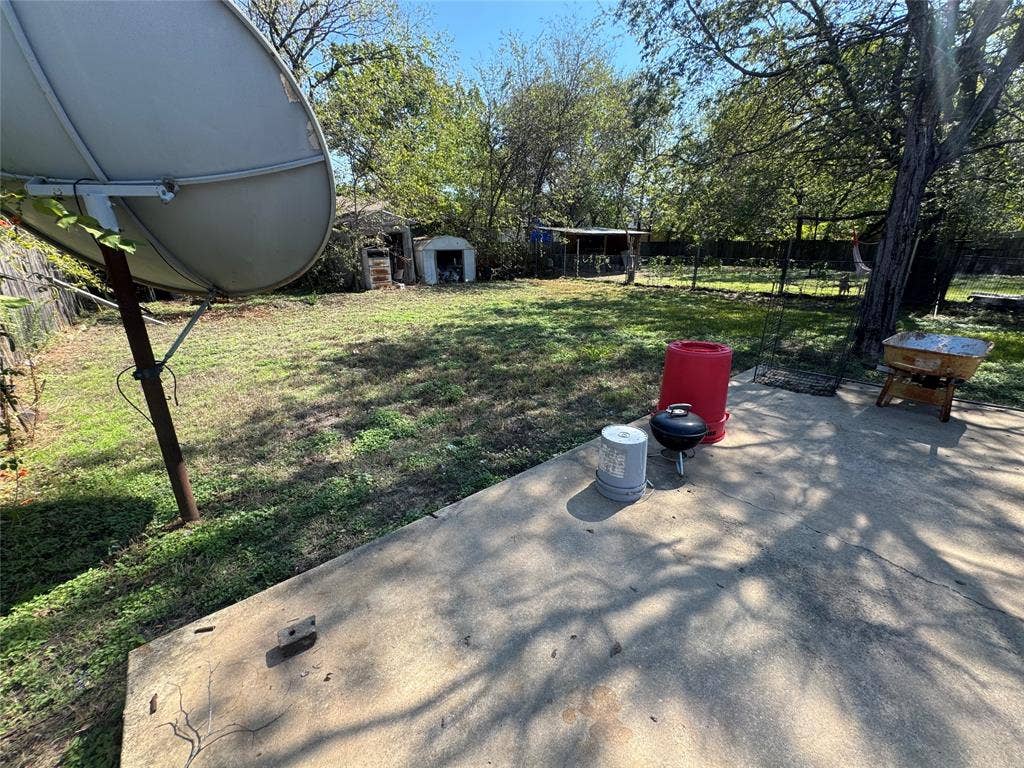 544 Pleasant Meadows Lane, Dallas, TX 75217 Concrete patio featuring an expansive backyard, mature trees, and detached storage structures