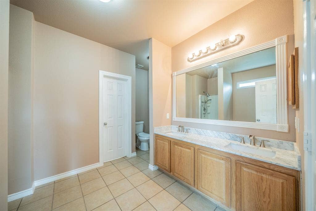 1739 Chadwick Drive, Cedar Hill, TX 75104 Master bathroom with dual sinks, granite countertop, decorative mirror frame and medicine cabinet.