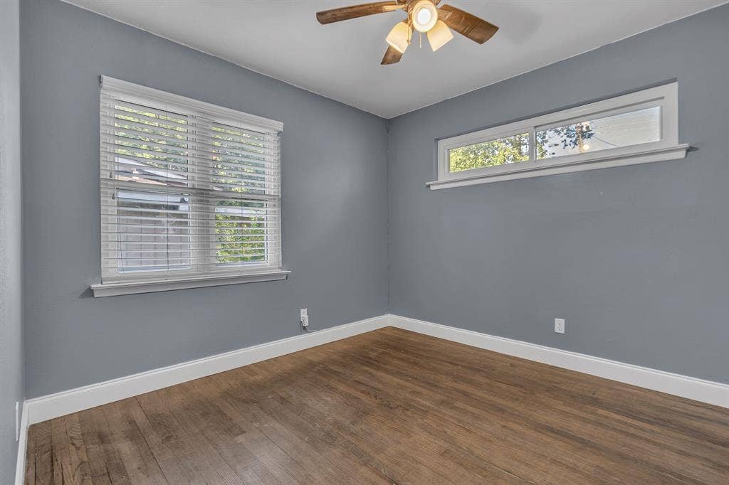 9621 Rustown Drive, Dallas, TX 75228 Wood-finish flooring, two distinct window styles, white trim, and a ceiling fan with integrated lighting