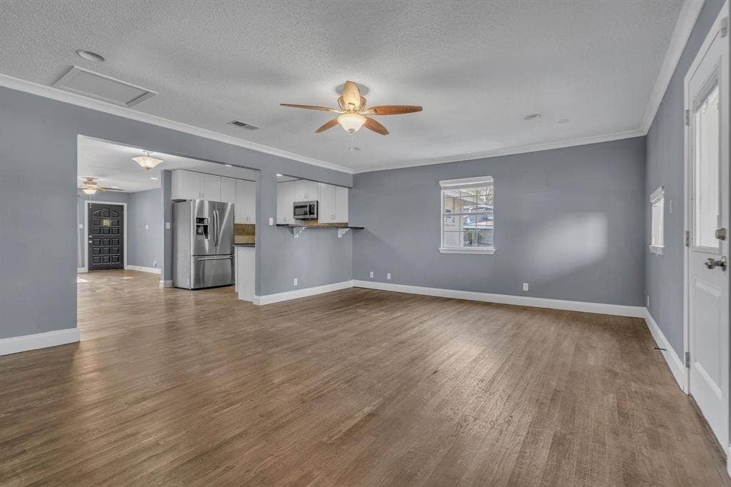 9621 Rustown Drive, Dallas, TX 75228 Spacious living area featuring wood-finish flooring, a ceiling fan, and crown molding