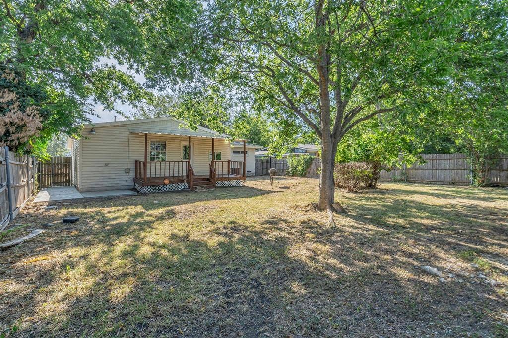 9621 Rustown Drive, Dallas, TX 75228 Expansive yard featuring mature trees, a covered porch with railings, horizontal siding, and a privacy fence