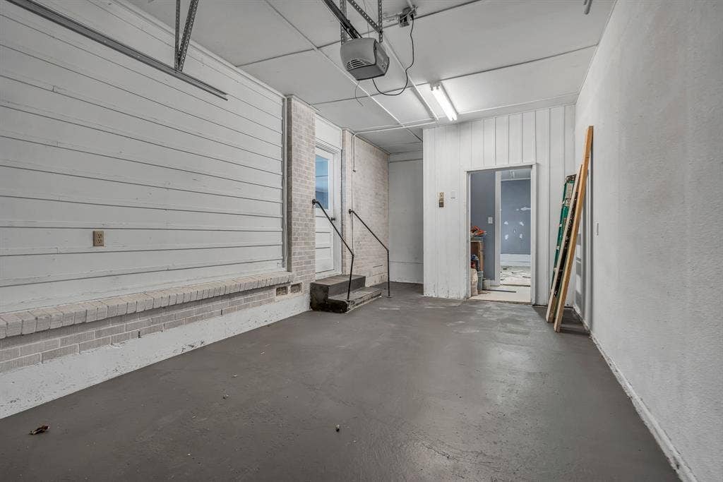 9621 Rustown Drive, Dallas, TX 75228 Garage with a gray finished floor, overhead lighting, and a white paneled wall