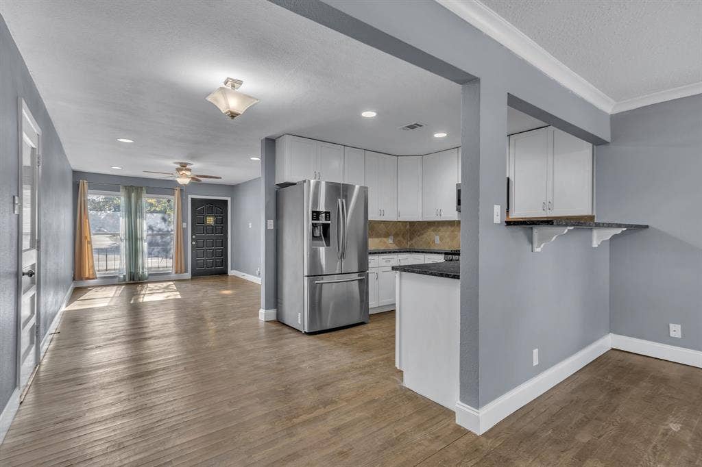 9621 Rustown Drive, Dallas, TX 75228 Kitchen with white cabinetry, stainless steel refrigerator, dark countertops, and a built-in breakfast bar