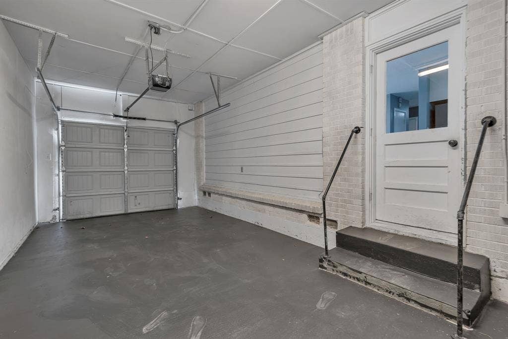 Attached garage featuring an overhead door, smooth concrete flooring, and an additional entry door with a glass panel