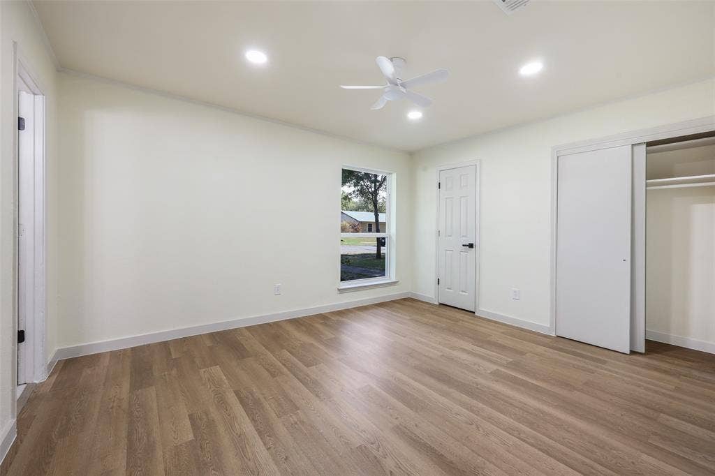 Wood-finish flooring with recessed lighting, ceiling fan, and sliding closet doors