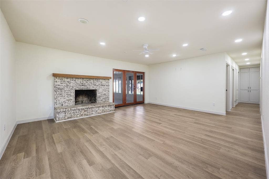 Spacious room featuring wood-finish flooring, a brick fireplace with a wood mantel, recessed lighting, and built-in cabinetry