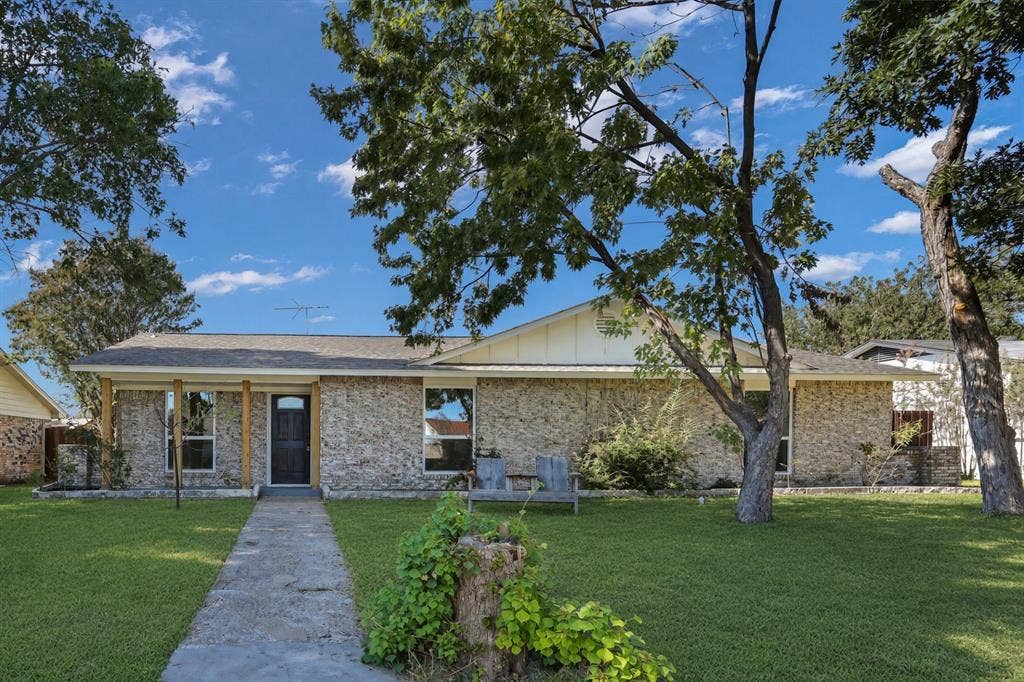 Stone veneer exterior with wood columns, a dark entry door, and a concrete walk