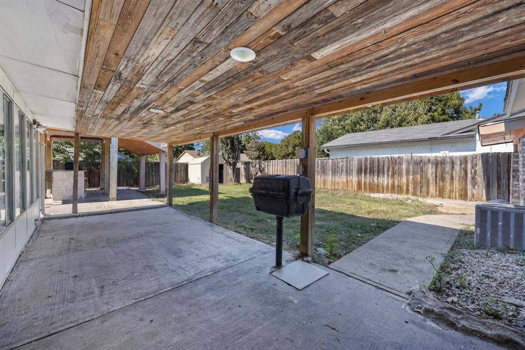 Covered patio with a wood-plank ceiling, concrete flooring, and an expansive fenced yard