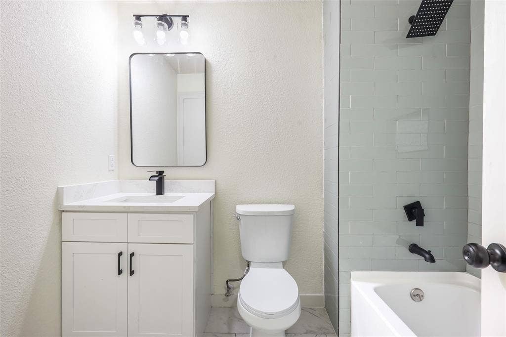 White vanity with a light-toned countertop, black faucet, and rectangular mirror