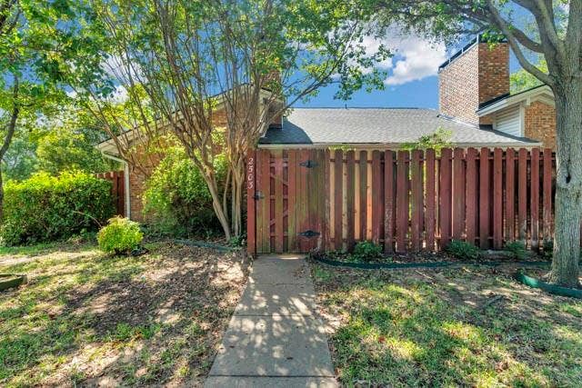 2503 Shady Ridge Drive, Bedford, TX 76021 Brick exterior with a prominent chimney, concrete walkway, and wood privacy fencing