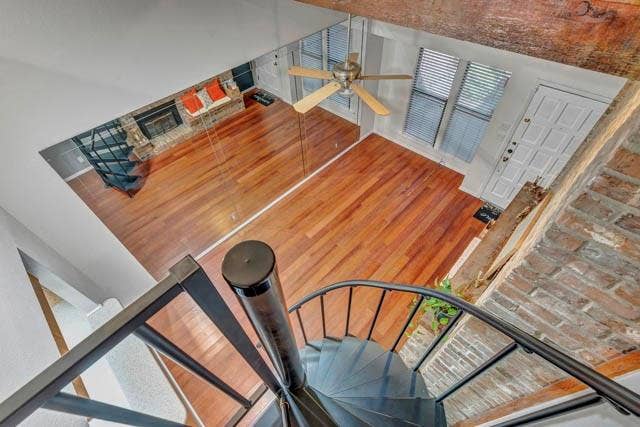 2503 Shady Ridge Drive, Bedford, TX 76021 Open-concept living space featuring wood-finish flooring, vaulted ceilings with exposed timber beams, a brick fireplace, and a metal spiral staircase