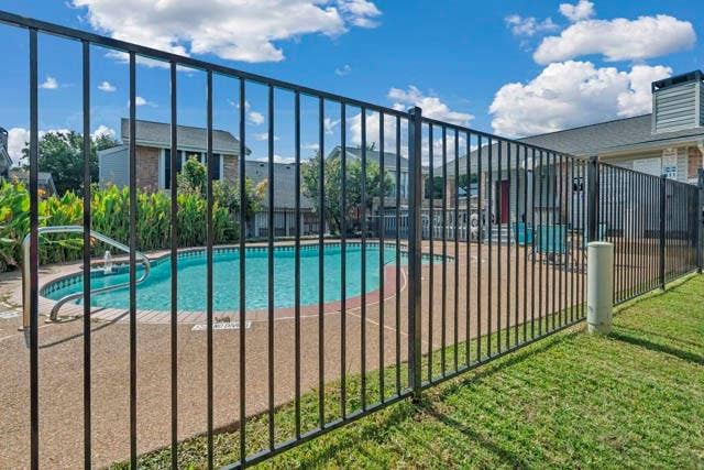 2503 Shady Ridge Drive, Bedford, TX 76021 In-ground pool with aggregate pool decking, enclosed by a black metal security fence, set against a manicured lawn