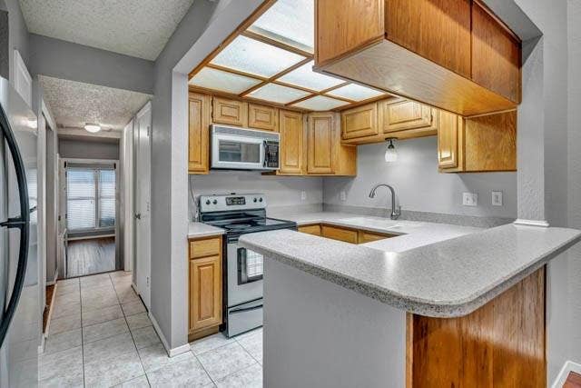 2503 Shady Ridge Drive, Bedford, TX 76021 Kitchen featuring wood cabinetry, stone-finish countertops, stainless steel appliances, a tile floor, and an integrated ceiling light grid