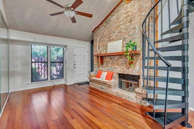 2503 Shady Ridge Drive, Bedford, TX 76021 Vaulted ceiling, wood-finish flooring, floor-to-ceiling brick fireplace with a wood mantel, and a metal spiral staircase
