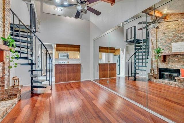 2503 Shady Ridge Drive, Bedford, TX 76021 Vaulted ceiling featuring a metal spiral staircase, wood-finish flooring, floor-to-ceiling mirror wall, and a floor-to-ceiling brick fireplace