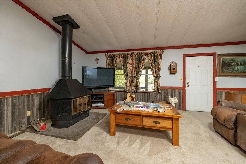 Freestanding black metal fireplace on a stone hearth, featuring wood-panel wainscoting and vaulted ceilings
