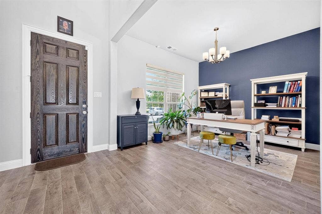 Entryway featuring wood-finish flooring, a six-panel dark wood door, a multi-light chandelier, and a prominent navy blue accent wall