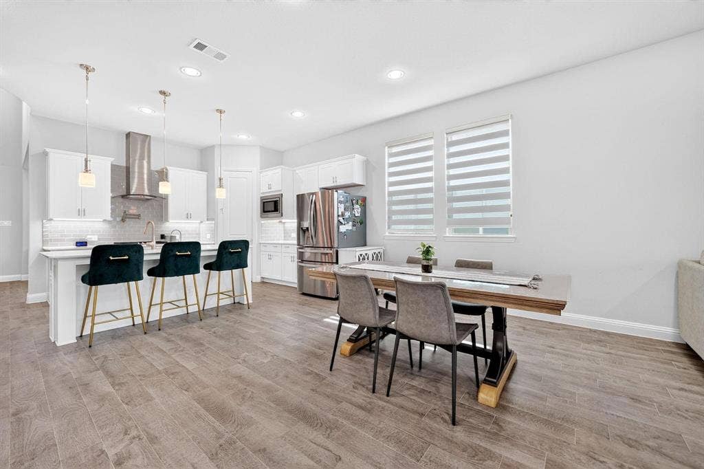 Kitchen featuring white cabinetry, quartz countertops, a stainless steel chimney-style range hood, recessed lighting, and wood-finish flooring
