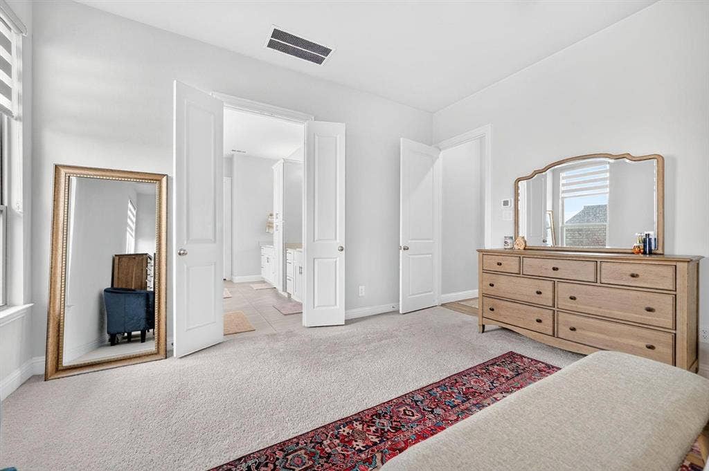 Neutral-toned interior space featuring light-colored wall-to-wall carpeting, white two-panel interior doors, and a double-door entryway