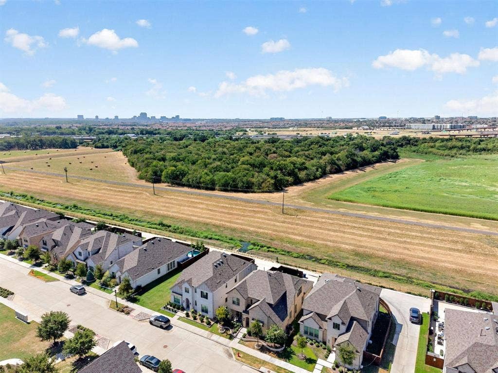 Aerial perspective of a suburban neighborhood featuring multi-story residences with pitched shingle roofs, concrete driveways, and expansive open space