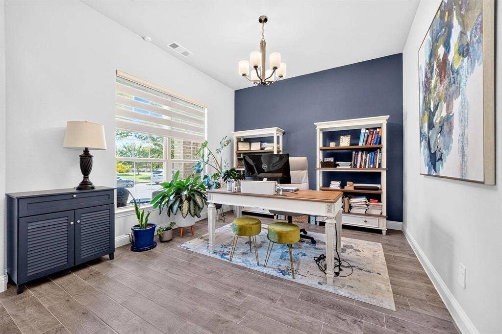 Room featuring wood-finish tile flooring, a deep-toned accent wall, large window with integrated blinds, and a multi-arm chandelier