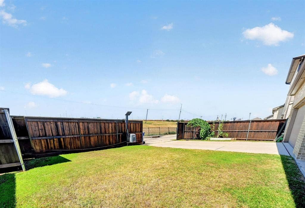 Rear exterior featuring a manicured lawn, concrete patio, and wood privacy fencing