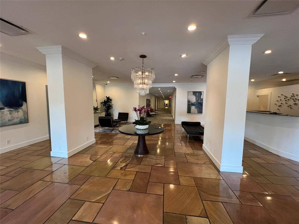3883 Turtle Creek Boulevard, #907, Dallas, TX 75219 Spacious common area featuring varied stone flooring, recessed lighting, a tiered chandelier, and decorative columns