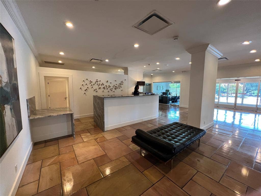 3883 Turtle Creek Boulevard, #907, Dallas, TX 75219 Irregular-cut stone flooring, built-in reception desk with a stone countertop, recessed lighting, crown molding, and expansive glass entry doors