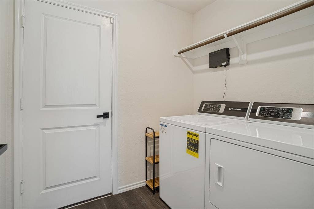 1506 Buckaroo Lane, Josephine, TX 75189 Laundry area featuring a wood-finish floor, a painted interior door with matte black hardware, and an overhead shelf with a built-in clothing rod
