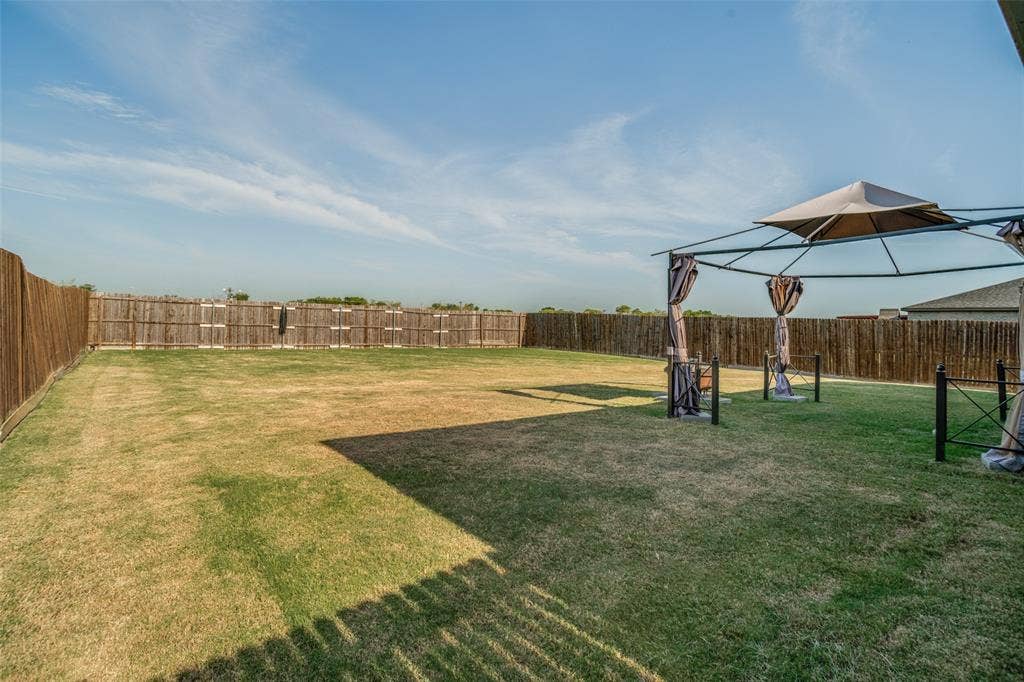 1506 Buckaroo Lane, Josephine, TX 75189 Expansive backyard featuring a level grass lawn and full-perimeter wood fencing