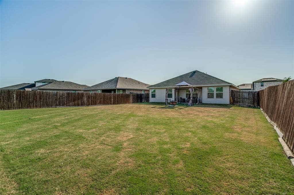 1506 Buckaroo Lane, Josephine, TX 75189 Expansive backyard featuring a level lawn, full-perimeter wood fencing, and a covered patio area