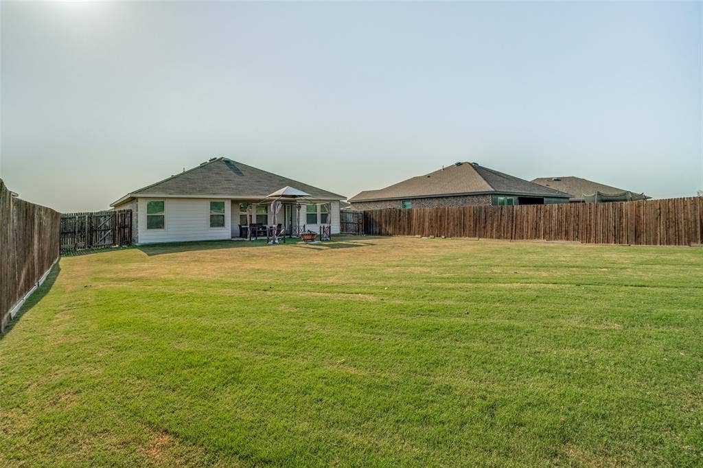 1506 Buckaroo Lane, Josephine, TX 75189 Expansive backyard featuring a large grass lawn, perimeter wood fencing, and a concrete patio