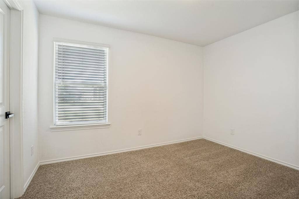1506 Buckaroo Lane, Josephine, TX 75189 Neutral-toned wall-to-wall carpeting, crisp white walls, and a single-hung window outfitted with horizontal blinds